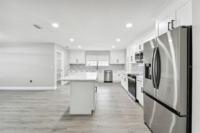 kitchen featuring white cabinets, appliances with stainless steel finishes, light hardwood / wood-style floors, and a kitchen island