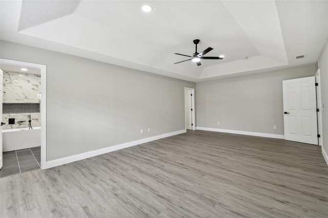 spare room featuring hardwood / wood-style flooring, ceiling fan, and a tray ceiling