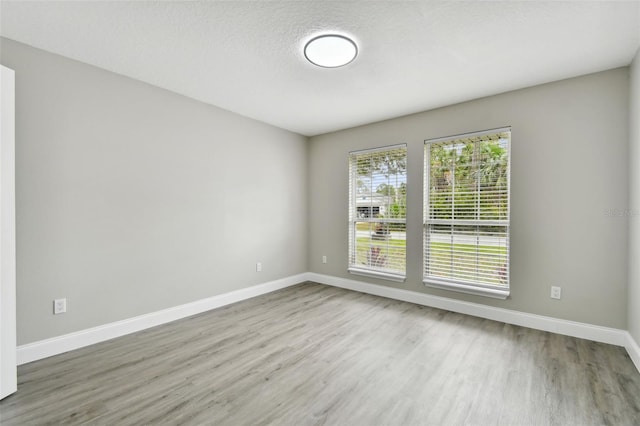 unfurnished room with a textured ceiling and light wood-type flooring