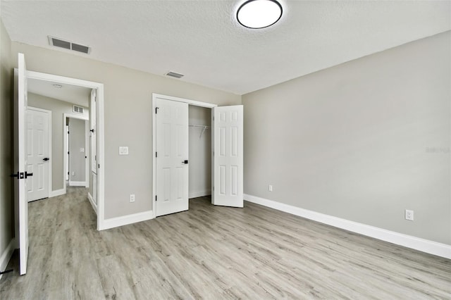 unfurnished bedroom with a closet, a textured ceiling, and light hardwood / wood-style flooring