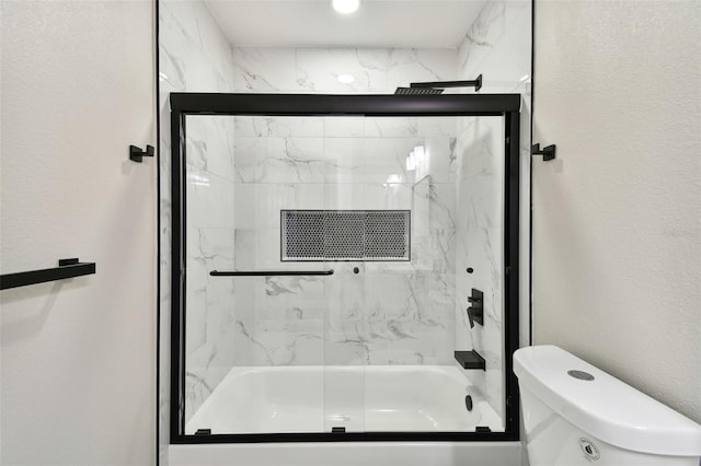 bathroom featuring bath / shower combo with glass door and toilet