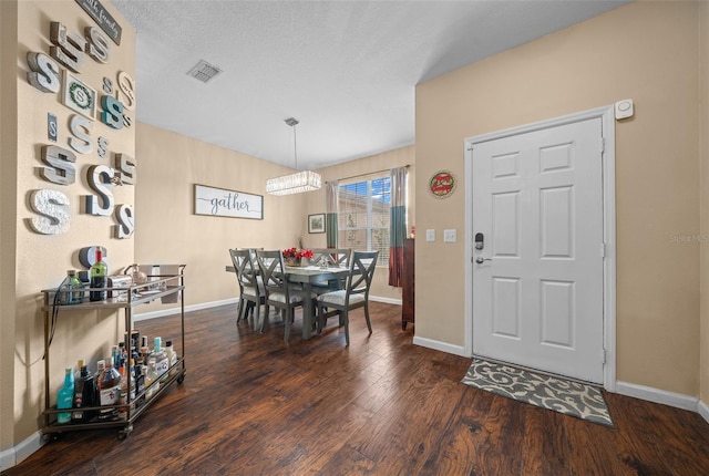 dining room featuring dark hardwood / wood-style flooring, a chandelier, and a textured ceiling