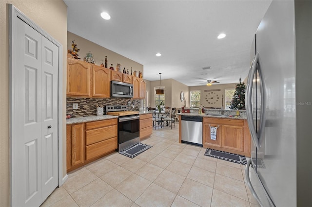 kitchen with backsplash, sink, ceiling fan, appliances with stainless steel finishes, and decorative light fixtures