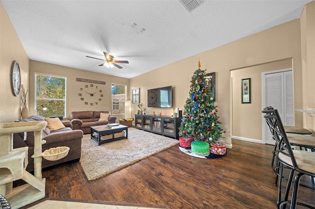 living room featuring a textured ceiling, dark hardwood / wood-style floors, and ceiling fan