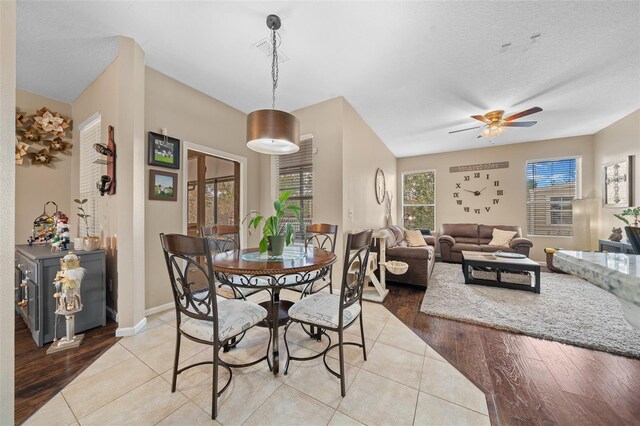 dining room with ceiling fan, light wood-type flooring, and a textured ceiling