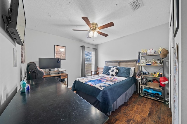 bedroom with ceiling fan, dark wood-type flooring, and a textured ceiling