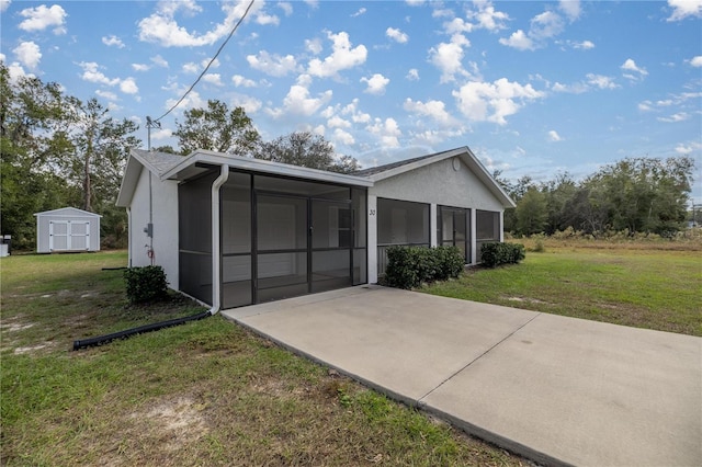 ranch-style house with a sunroom, a front lawn, and a storage unit