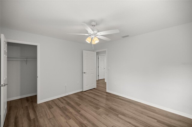 unfurnished bedroom with ceiling fan, a closet, and wood-type flooring