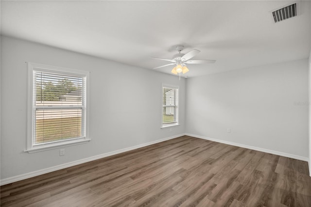 spare room featuring ceiling fan, a healthy amount of sunlight, and dark hardwood / wood-style floors