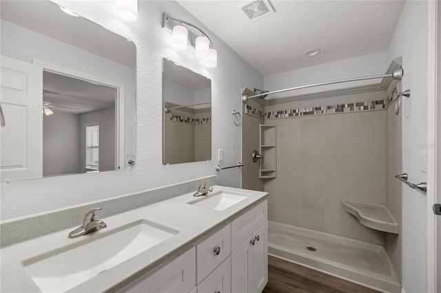 bathroom featuring walk in shower, vanity, hardwood / wood-style flooring, and ceiling fan