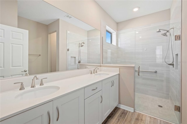 bathroom with hardwood / wood-style floors, vanity, and a shower with door