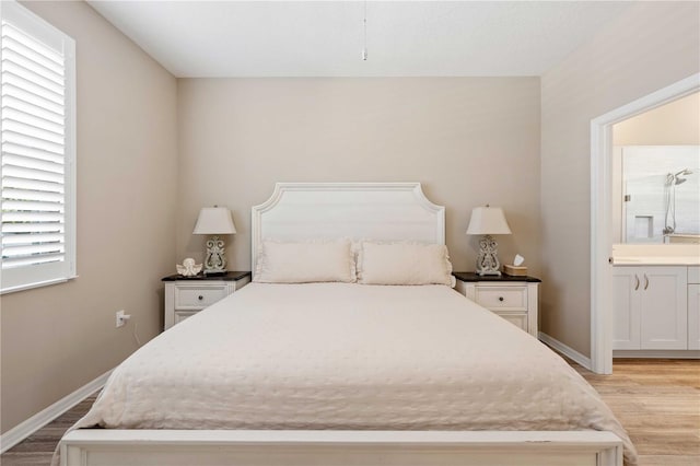 bedroom with light wood-type flooring and connected bathroom