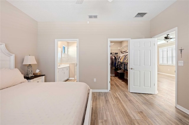 bedroom with a spacious closet, light hardwood / wood-style flooring, connected bathroom, and a closet