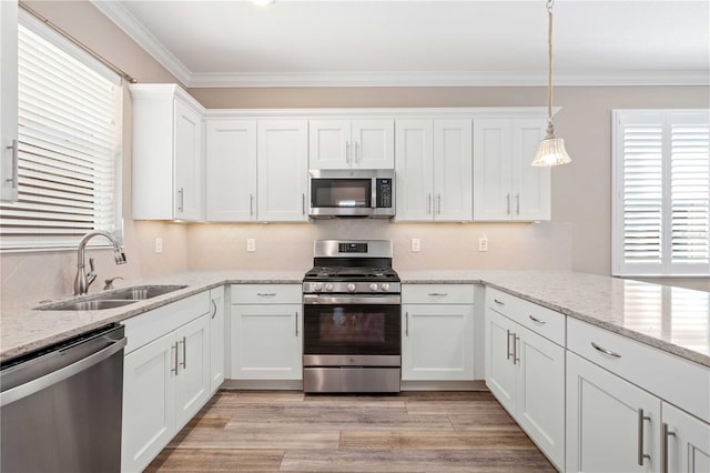 kitchen with sink, stainless steel appliances, light stone counters, decorative light fixtures, and white cabinets