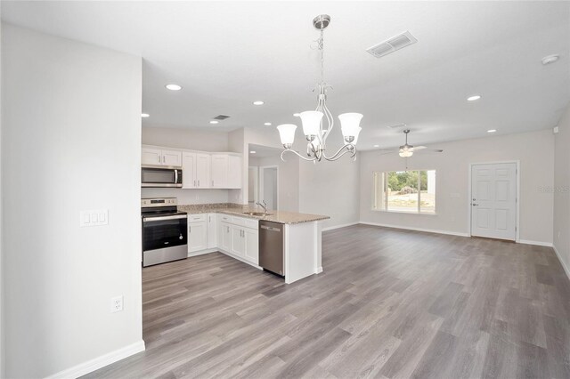 kitchen with white cabinetry, stainless steel appliances, kitchen peninsula, pendant lighting, and light hardwood / wood-style floors