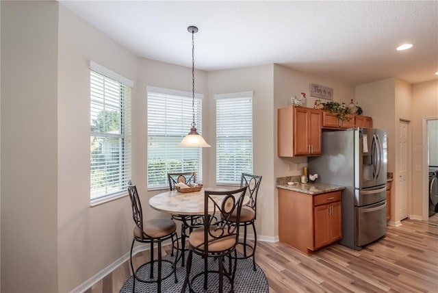 kitchen with stainless steel fridge with ice dispenser, light hardwood / wood-style flooring, a wealth of natural light, and pendant lighting