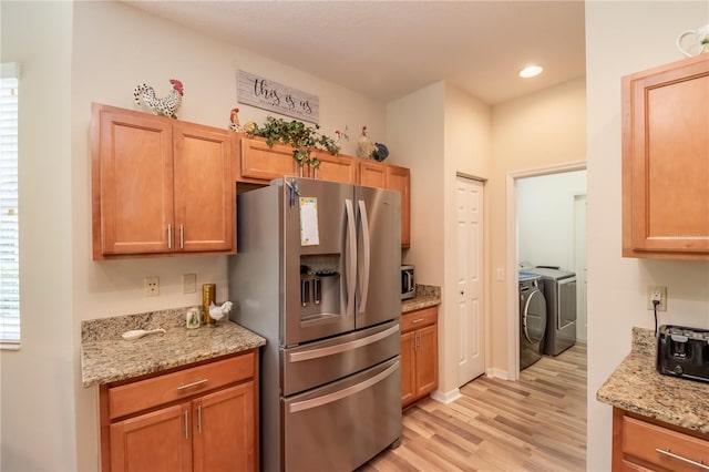 kitchen with separate washer and dryer, light stone countertops, light hardwood / wood-style flooring, and appliances with stainless steel finishes