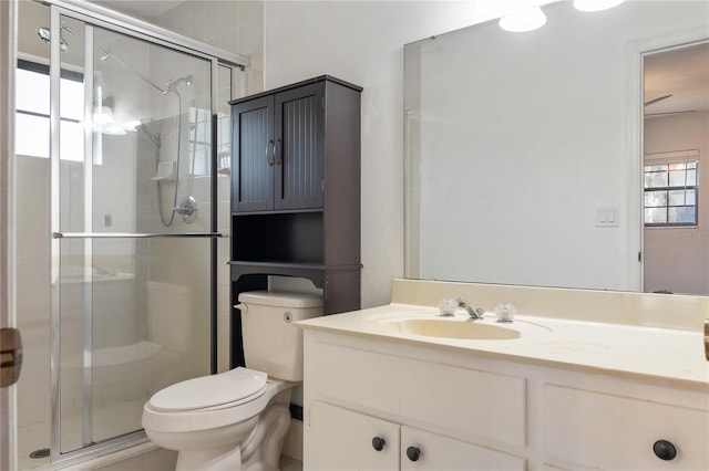 bathroom with ceiling fan, a shower with door, vanity, and toilet