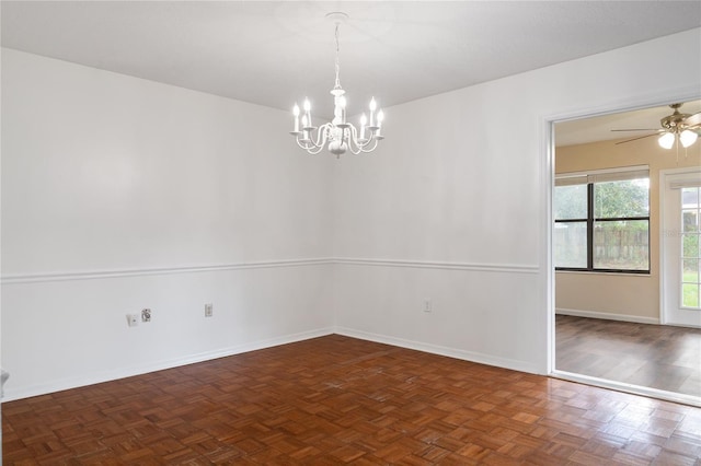 empty room with dark parquet flooring and ceiling fan with notable chandelier