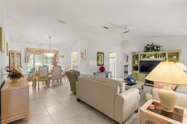 tiled living room with ceiling fan with notable chandelier and vaulted ceiling