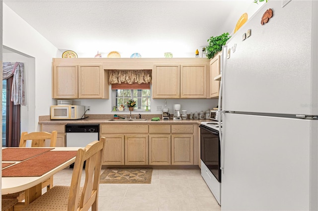 kitchen with light tile patterned flooring, white appliances, sink, and light brown cabinetry