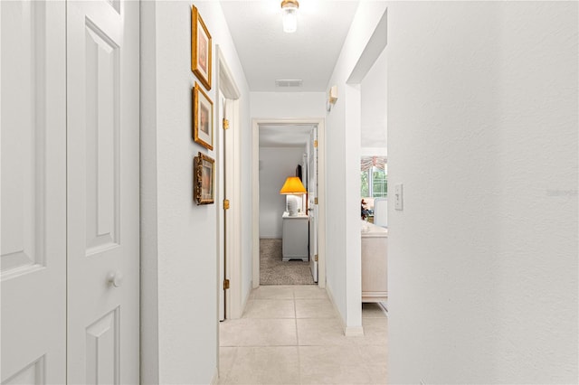 hallway with light tile patterned flooring and a textured ceiling