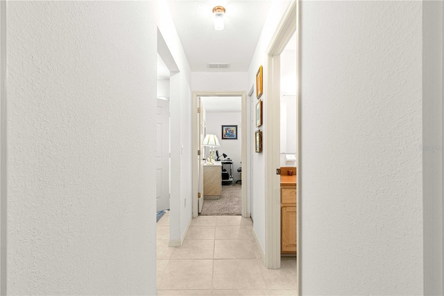 hallway featuring light tile patterned flooring and a textured ceiling