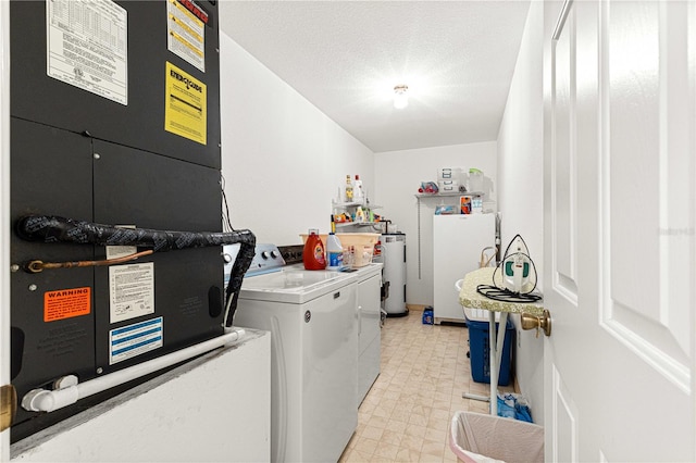 laundry room with a textured ceiling, washing machine and dryer, heating unit, and electric water heater