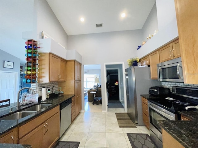 kitchen featuring appliances with stainless steel finishes, tasteful backsplash, dark stone countertops, and sink