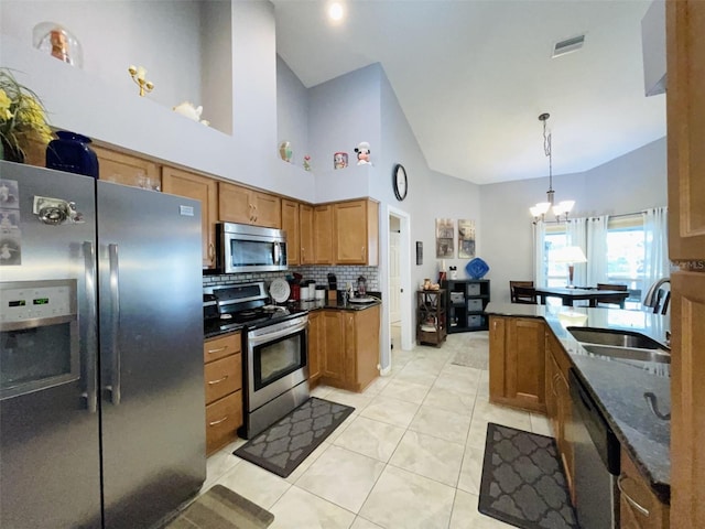 kitchen with stainless steel appliances, sink, light tile patterned floors, an inviting chandelier, and hanging light fixtures