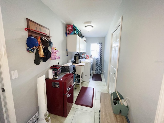 laundry area with cabinets, light tile patterned flooring, and washing machine and dryer