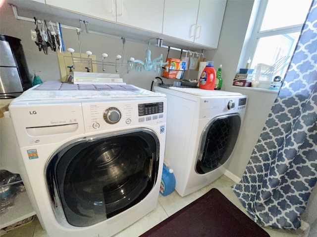 laundry room featuring washer and dryer, cabinets, and light tile patterned floors