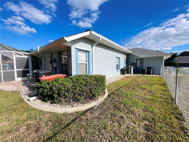 back of property with glass enclosure and a yard