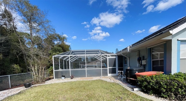 rear view of property featuring a lawn and glass enclosure