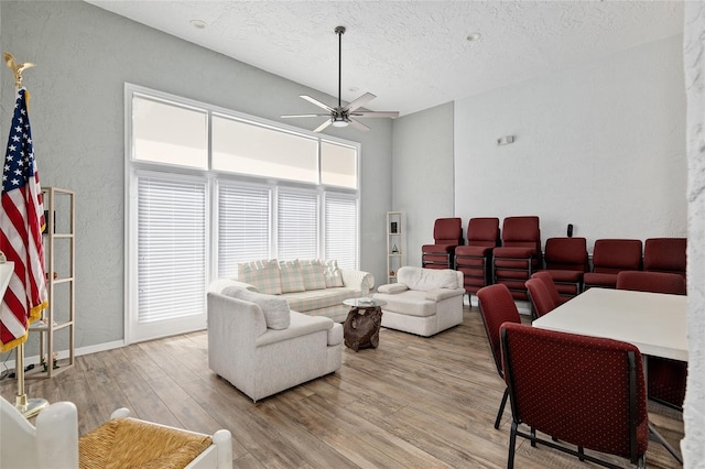 living room featuring a textured ceiling, light hardwood / wood-style flooring, and ceiling fan