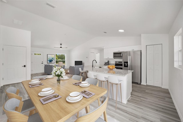 dining room featuring ceiling fan, light wood-type flooring, lofted ceiling, and sink