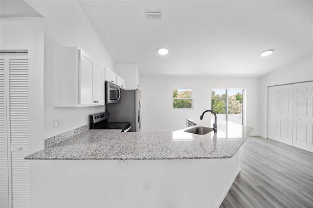 kitchen featuring range, sink, kitchen peninsula, light wood-type flooring, and white cabinetry