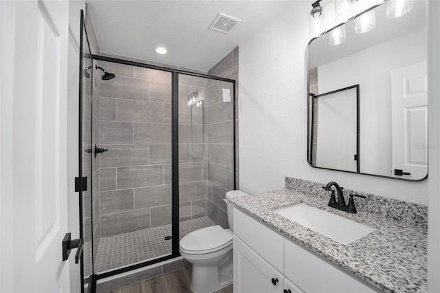 bathroom featuring vanity, toilet, a textured ceiling, an enclosed shower, and wood-type flooring