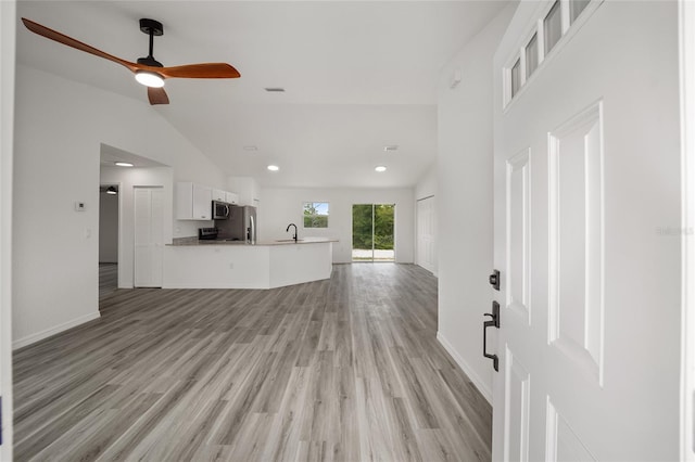 unfurnished living room featuring ceiling fan, sink, high vaulted ceiling, and light wood-type flooring