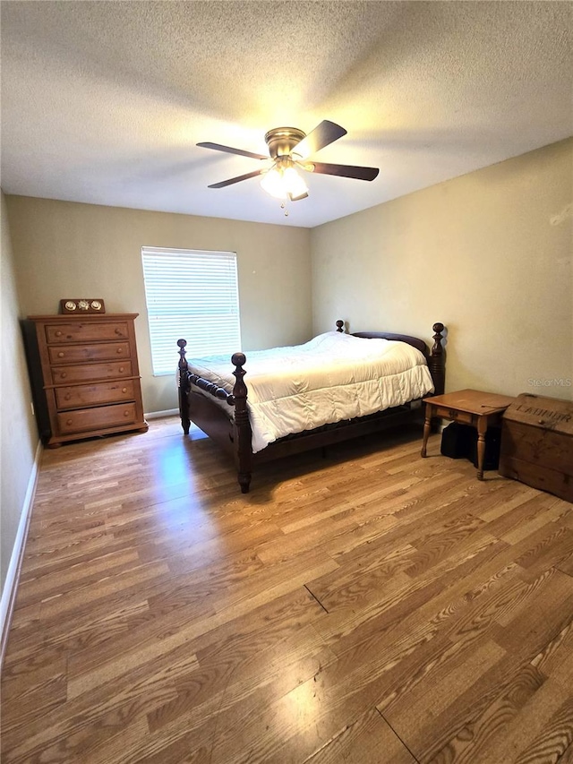 bedroom with ceiling fan, dark wood-type flooring, and a textured ceiling