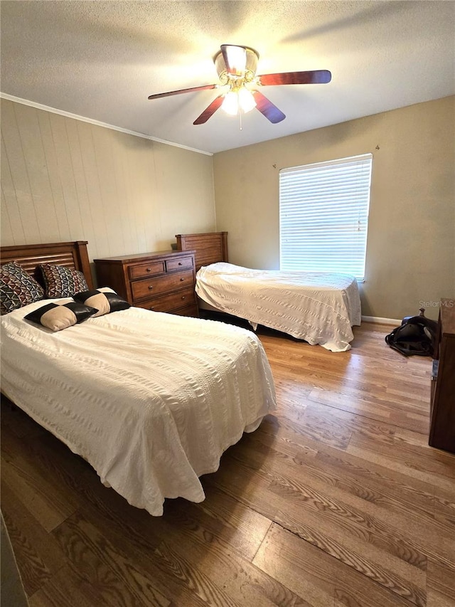 bedroom featuring hardwood / wood-style flooring, ceiling fan, crown molding, and a textured ceiling