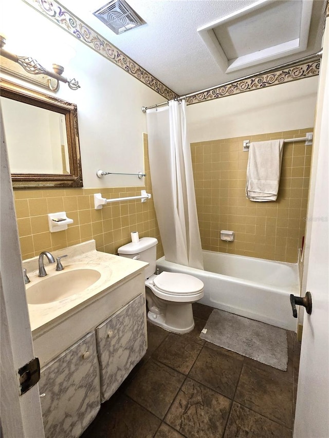 full bathroom featuring a textured ceiling, vanity, shower / bathtub combination with curtain, tile walls, and toilet