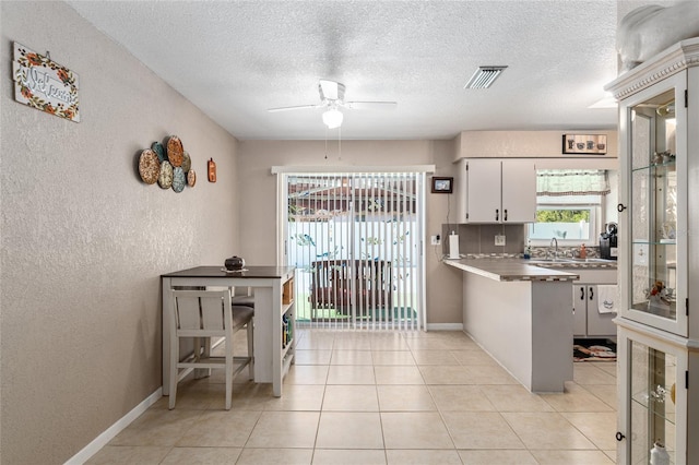 kitchen with kitchen peninsula, ceiling fan, white cabinets, and a textured ceiling