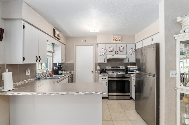 kitchen with sink, backsplash, kitchen peninsula, white cabinets, and appliances with stainless steel finishes