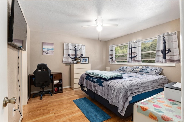 bedroom featuring a textured ceiling, light wood-type flooring, and ceiling fan