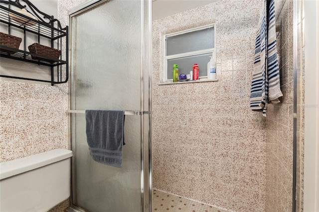 bathroom with a shower with shower door and toilet