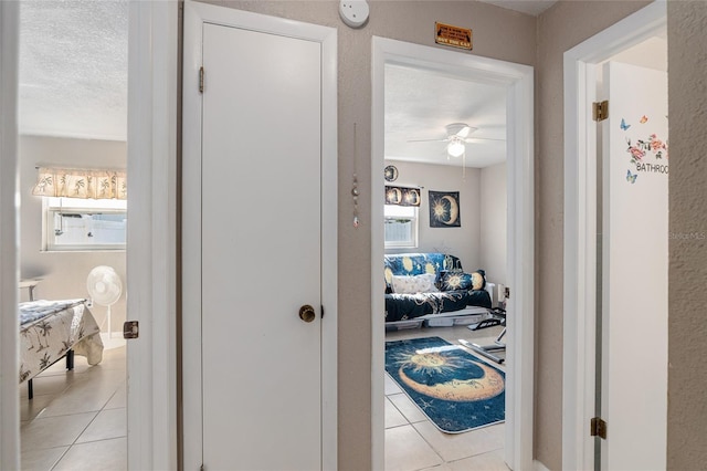 hallway with light tile patterned floors and a textured ceiling