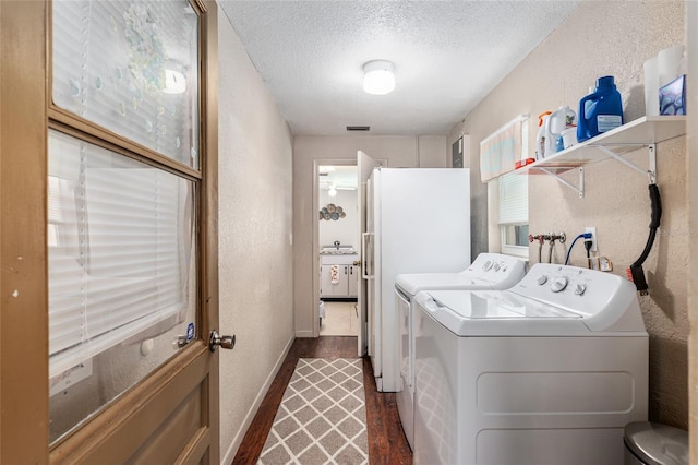 laundry area featuring a textured ceiling, separate washer and dryer, sink, and dark hardwood / wood-style floors