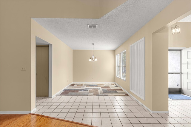 unfurnished dining area with a notable chandelier, light wood-type flooring, and a textured ceiling