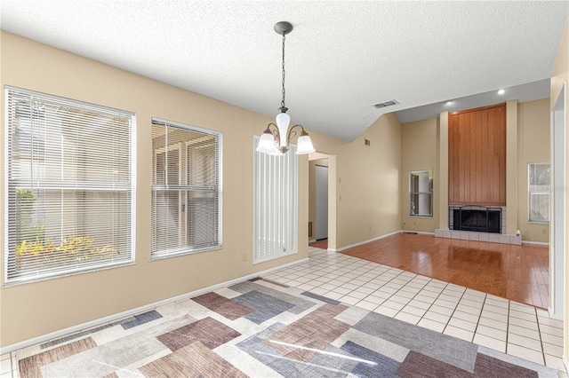 interior space with a fireplace, a textured ceiling, light hardwood / wood-style floors, and an inviting chandelier